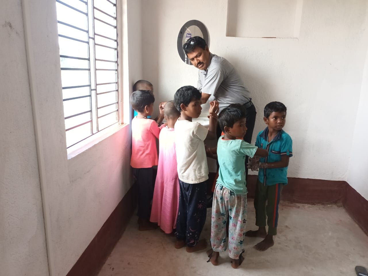 Children taking turns at a hand-washing session with a volunteer