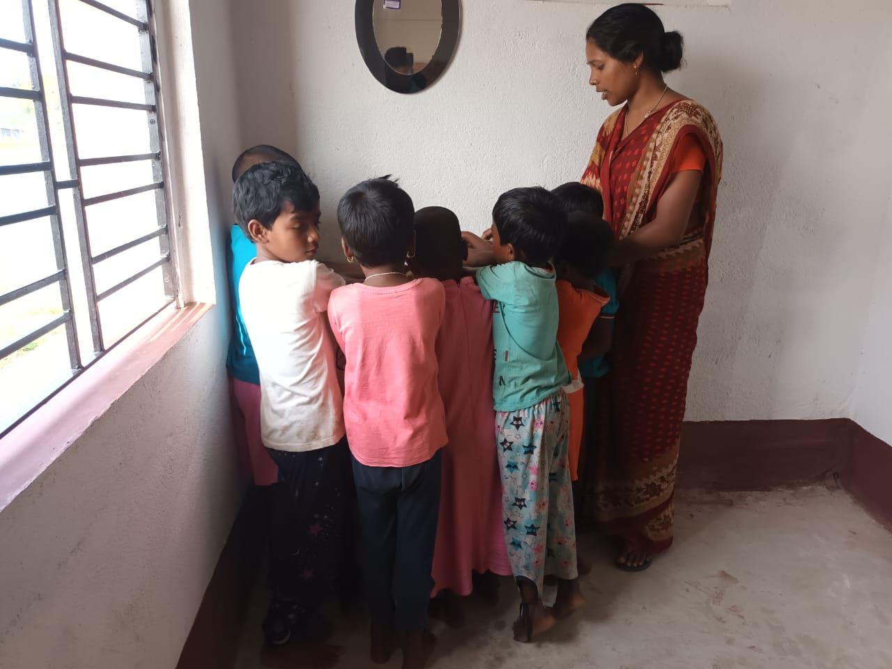A volunteer showing young children how to wash their hands at a basin