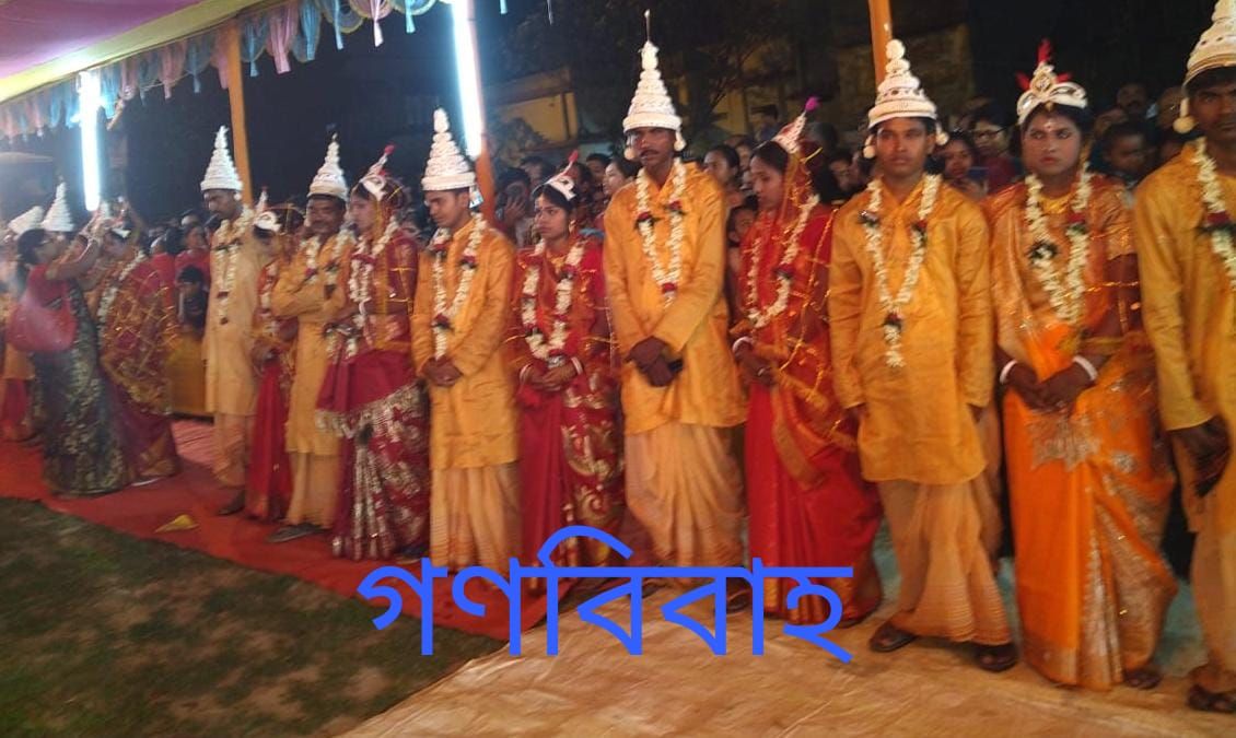 Couples in traditional Bengali wedding attire standing in a row at a mass wedding